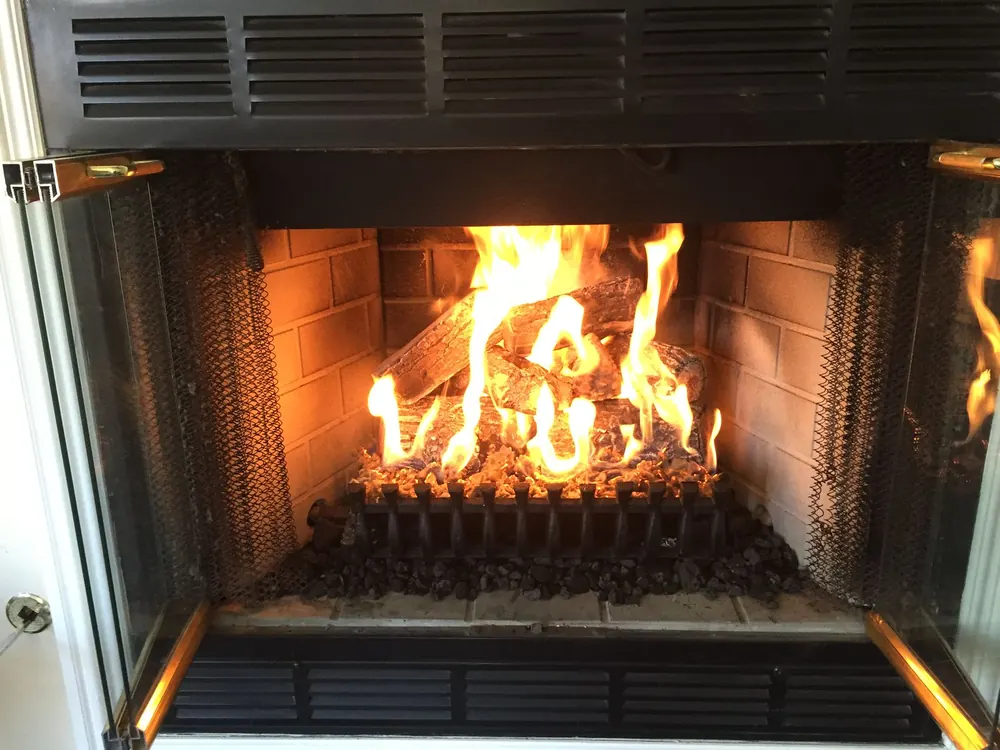 A gas log set burning in a brick firebox, installed by our crew