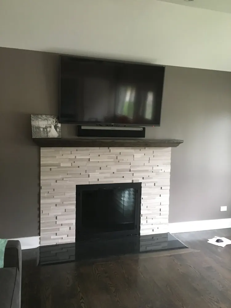 A stone fireplace and raised hearth beneath a wall-mounted TV