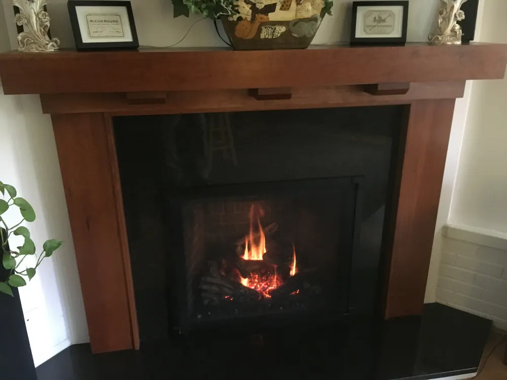 A big fire burning beneath a solid wood mantel